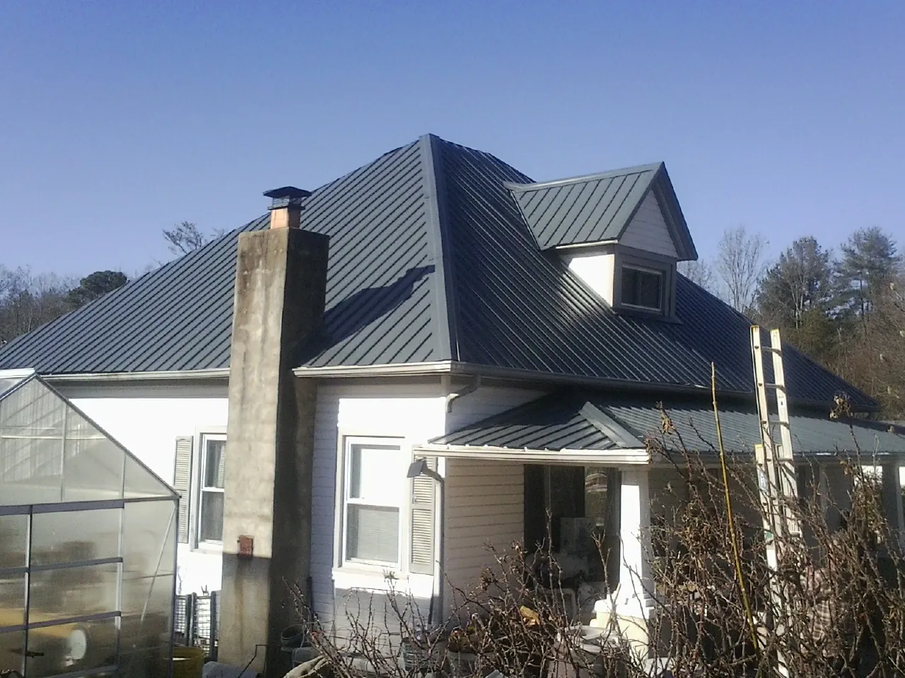 Dark blue standing seam metal roof on a white farmhouse with dormer — Slate & Tile Roof Repair by Roofing Brothers in Bear River City
