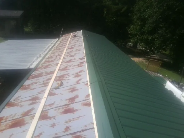Old rusted panels beside newly installed green metal roofing — Wind Damage Roof Repair by Roofing Brothers in Bear River City