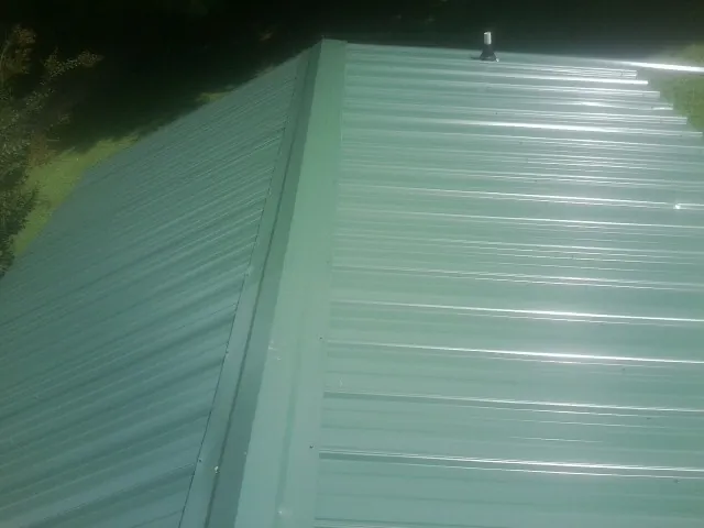 New green metal panels meeting at the ridge of a roof — Flat Roof Repair work by our crew in Bear River City