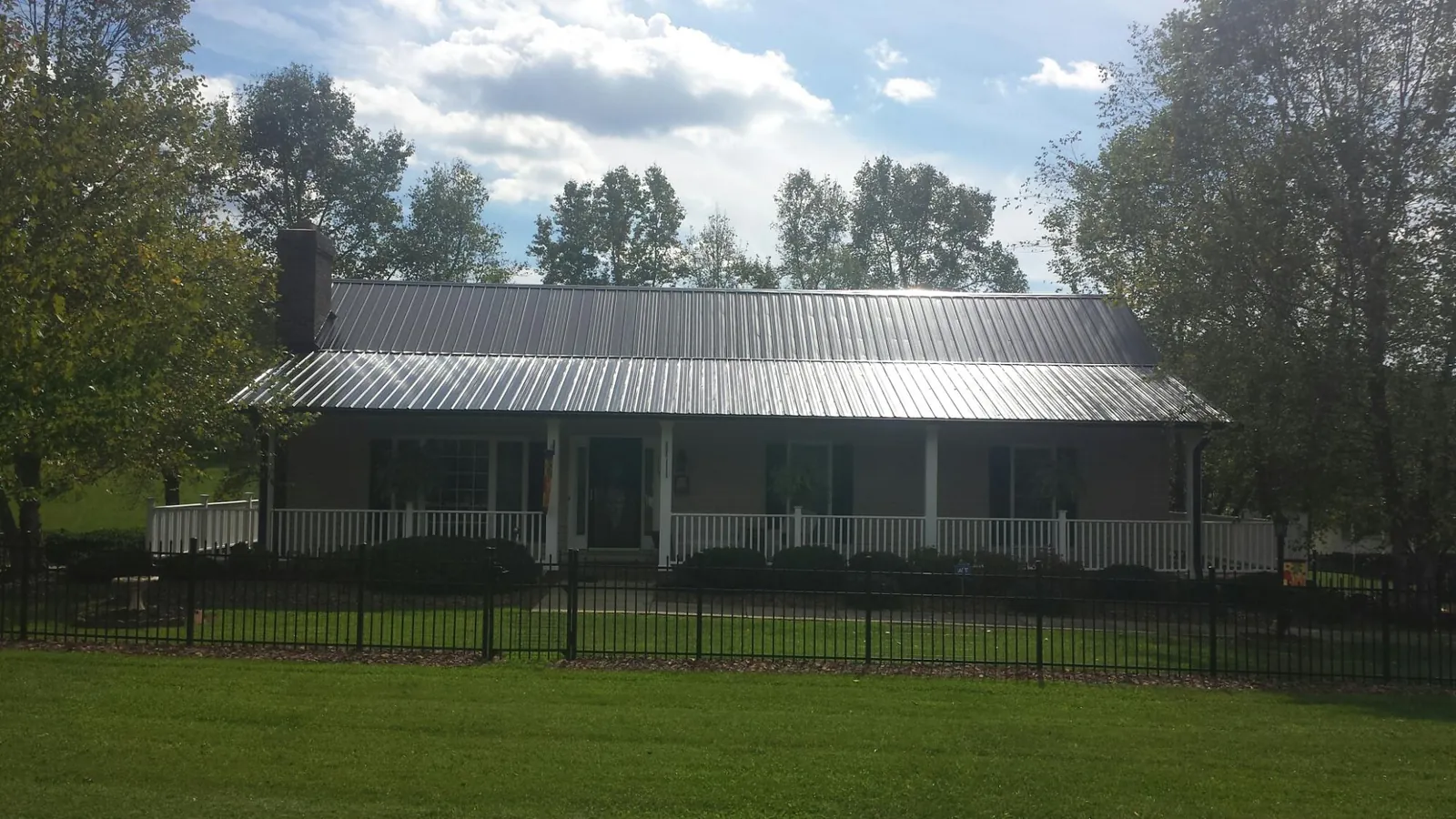 Gray metal roof on a brick ranch with a full width front porch — Gutter Guard Installation work by our crew in Bear River City