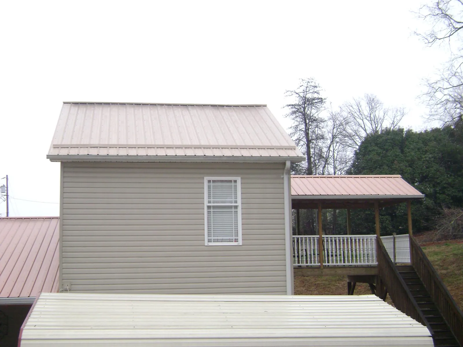 Tan metal roofs on a two story addition and attached porch, from a Roof Replacement job in Bear River City